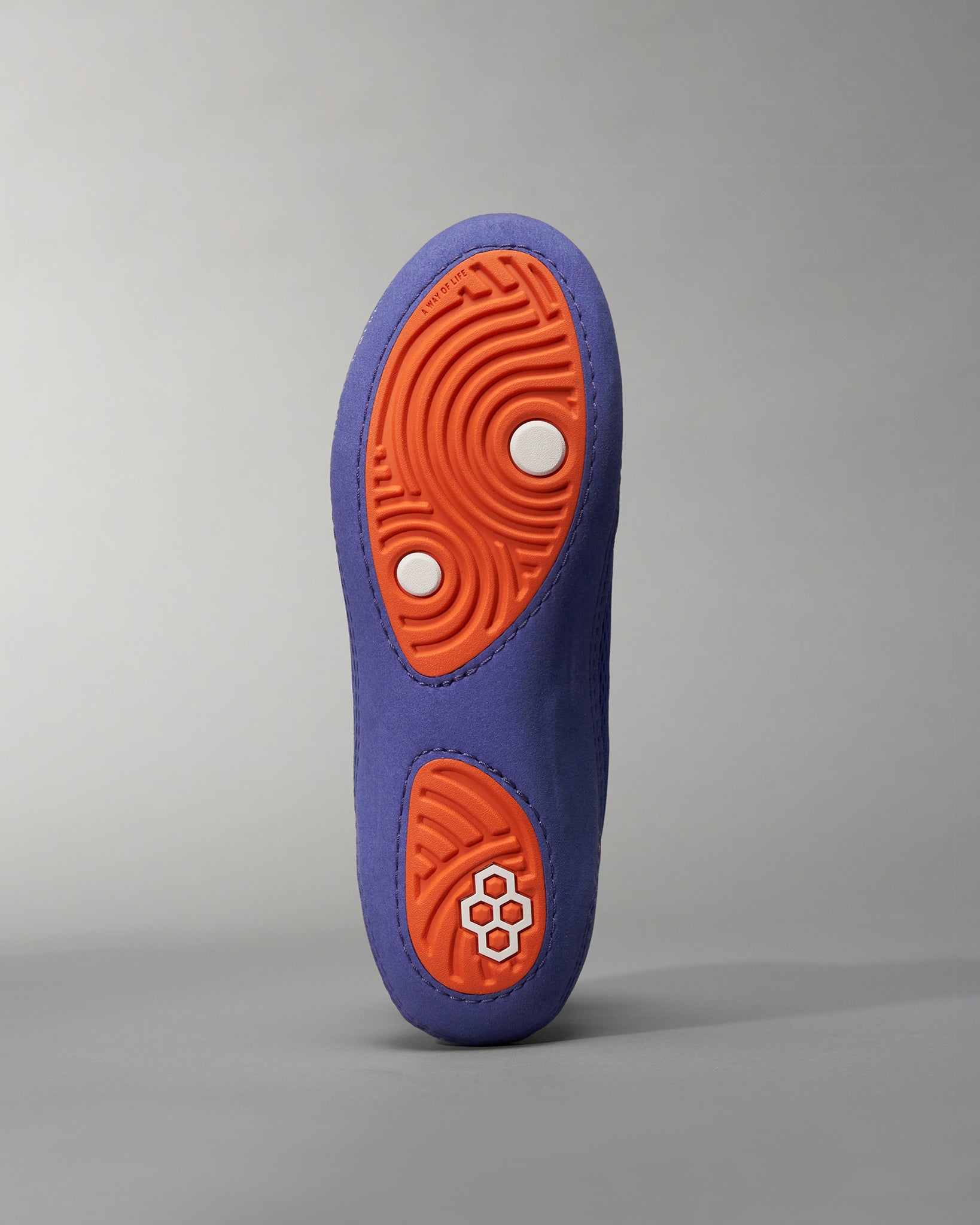 A colorful shoe sole featuring a purple exterior and an orange tread with white accents designed for traction and style