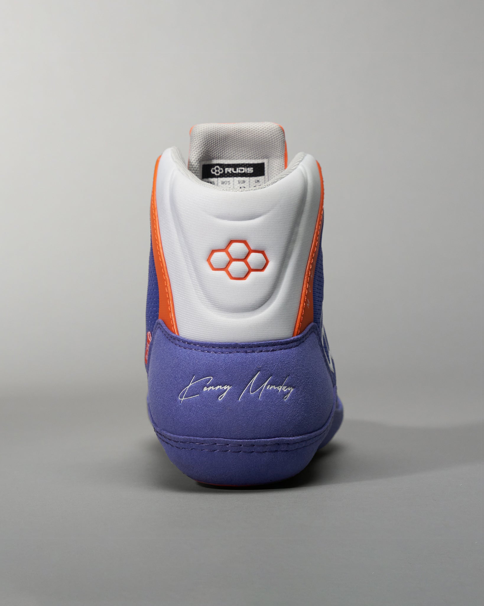 A close-up view of a purple athletic shoe with orange accents and a signature on the heel designed for performance and style in sports activities