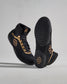 High-top athletic shoes in black with gold accents feature a textured upper and a detailed sole designed for grip, set against a light gray background.