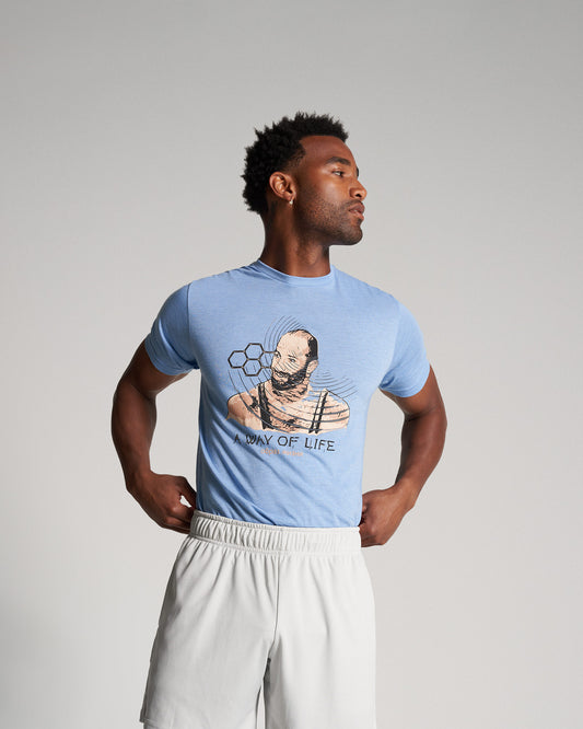 A man in a light blue t-shirt featuring an artistic graphic design paired with light shorts embodying a casual and sporty style