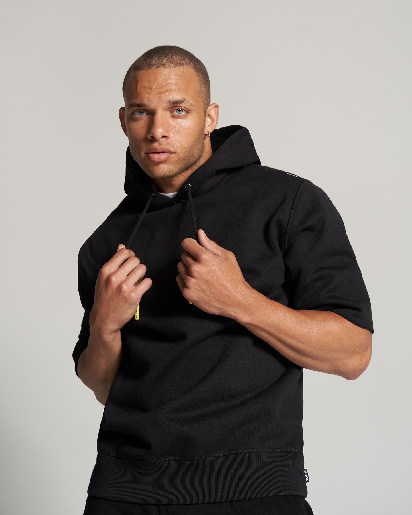 A young man poses confidently in a black hoodie showcasing a stylish and modern aesthetic