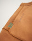 A close-up view of a brown garment sleeve featuring unique stitching details and an inscription reading A WAY OF LIFE