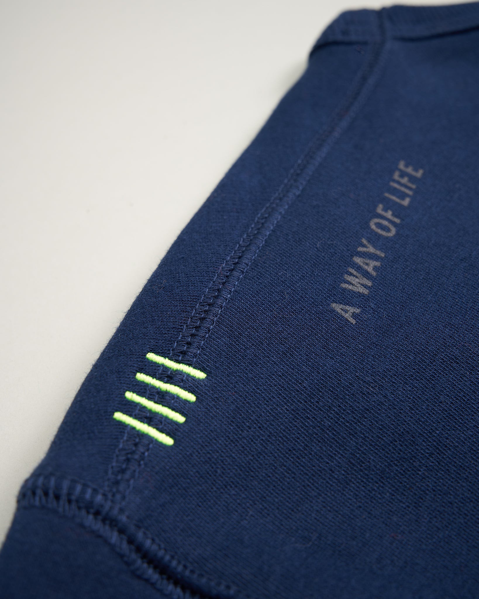 This close-up image features the sleeve of a navy blue garment emphasizing a motivational phrase and unique stitching details