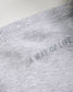 A close-up view of a light gray fabric with the phrase A WAY OF LIFE printed in subtle green text highlighting the texture and stitching details of the garment