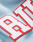 A close-up view of a light blue fabric featuring bold embroidered letters in white and red showcasing a clean and stylish design