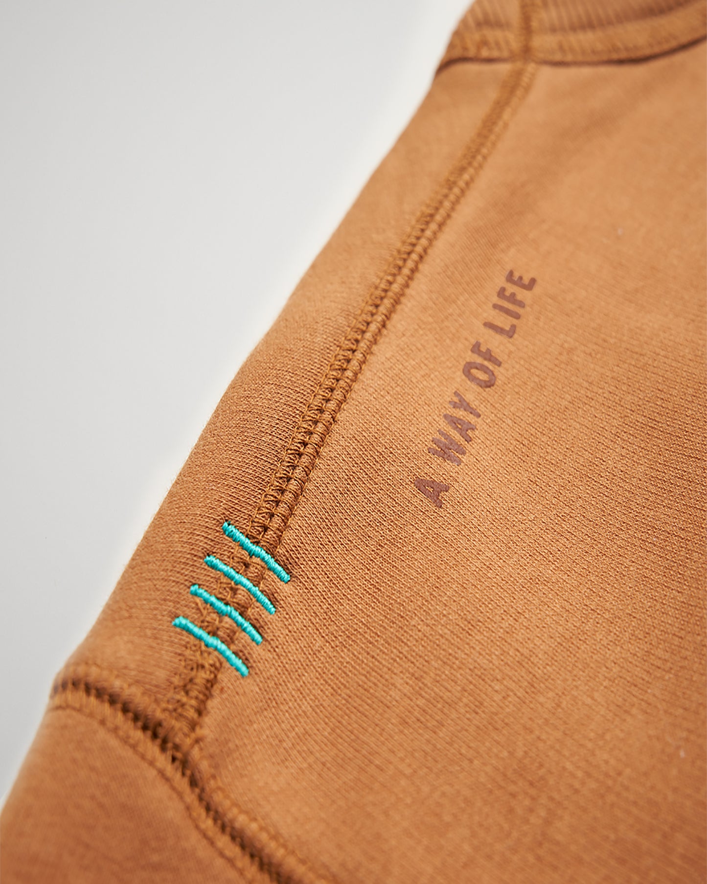 A close-up view of a brown garment showcasing unique stitching details and the phrase A WAY OF LIFE