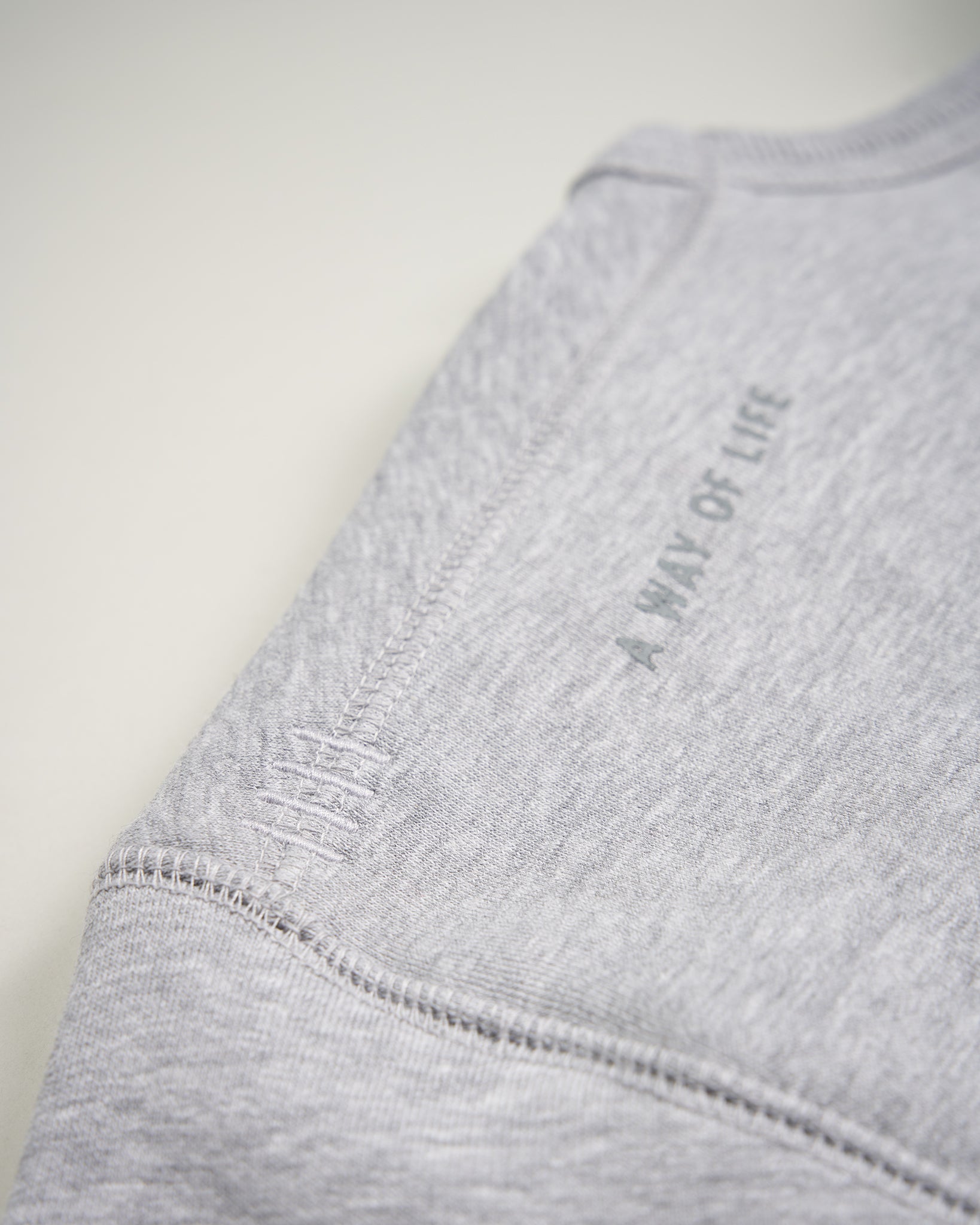 A close-up view of a gray sweatshirt sleeve featuring the phrase A WAY OF LIFE printed on it highlighting its soft texture and seam details