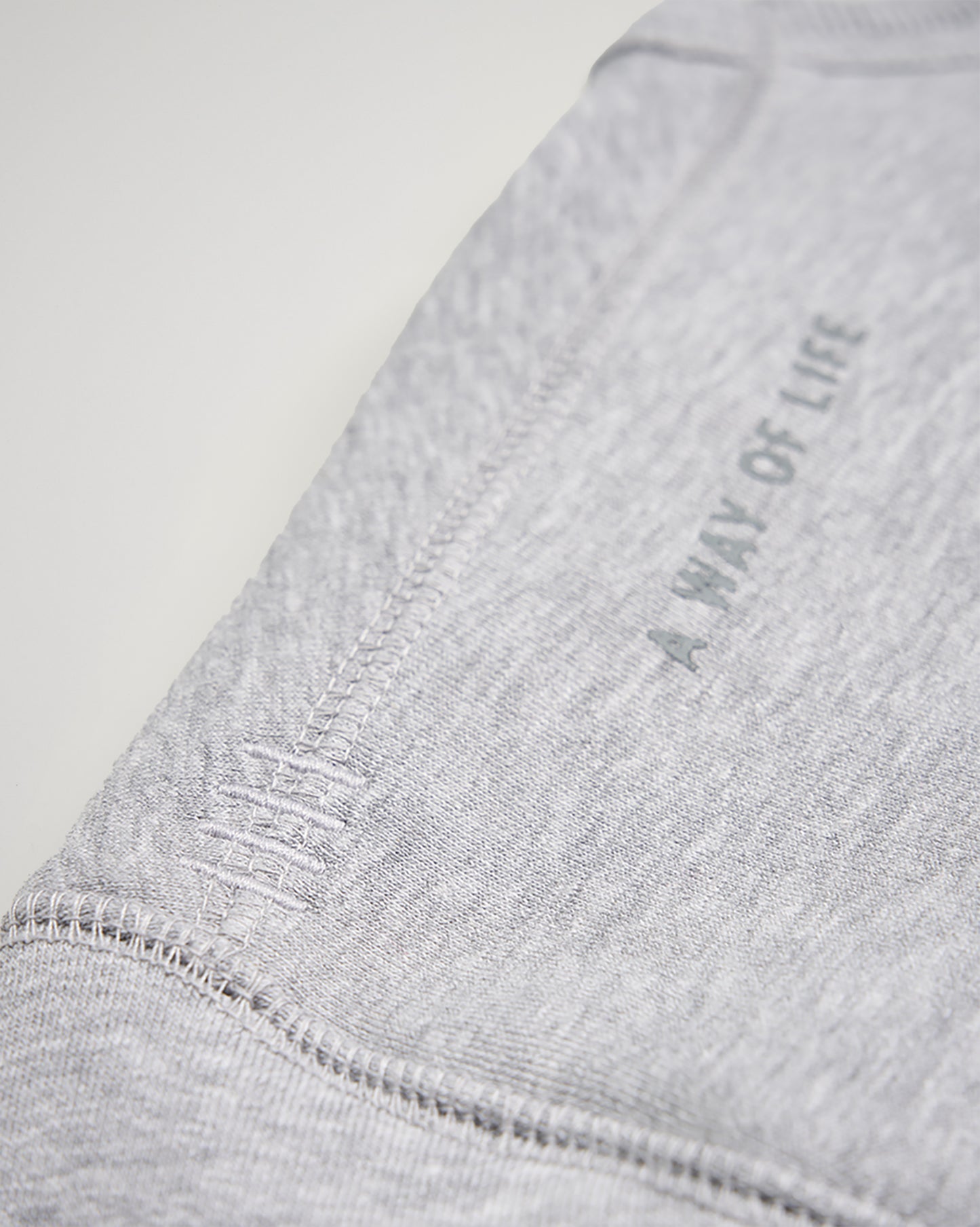 A close-up view of a light gray fabric with the phrase A WAY OF LIFE printed in a subtle design along the side