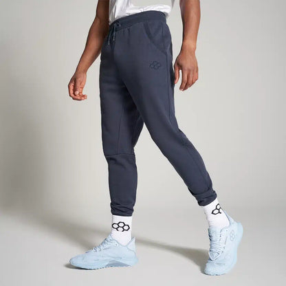 A stylish model showcasing dark gray jogger pants paired with light blue athletic shoes and sporty socks featuring a soccer ball motif