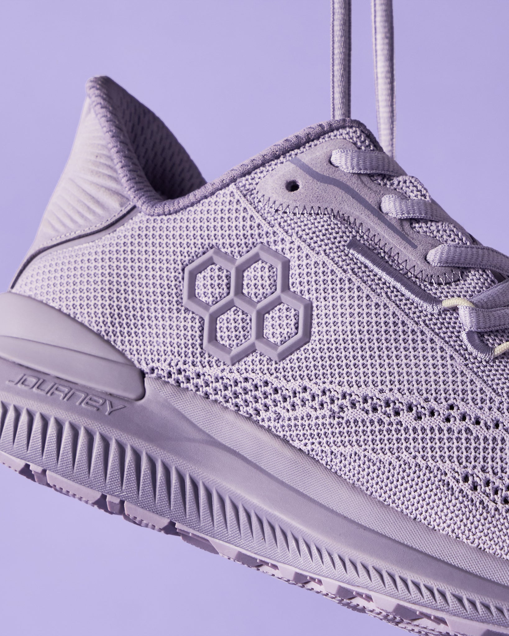 A close-up view of a light purple athletic shoe showcasing its intricate mesh design and modern branding elements