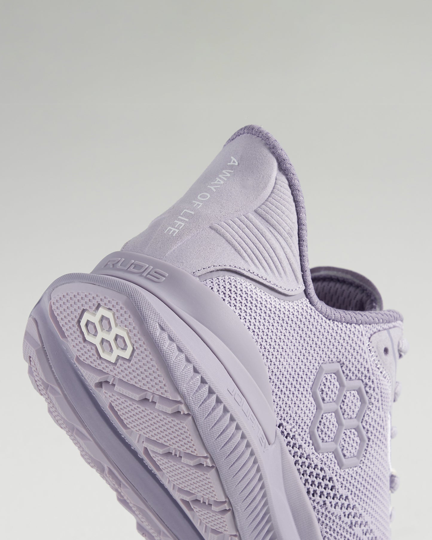 A close-up view of a stylish light purple athletic shoe with a breathable mesh upper and textured sole featuring the inscription A Way of Life and the brand name RUDIS