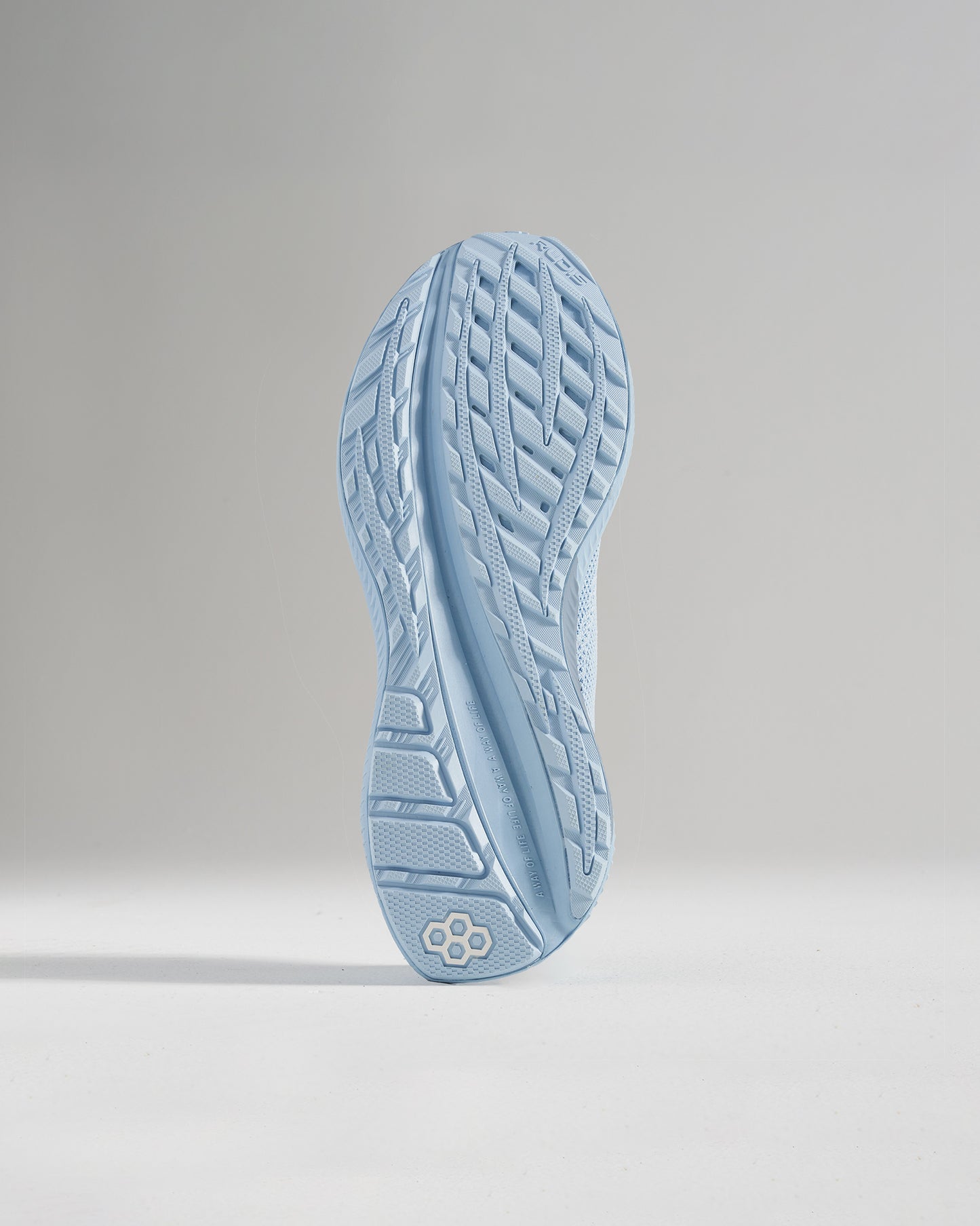 A close-up view of a light blue running shoe sole with an intricate tread pattern designed for grip and performance