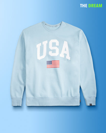 A light blue sweatshirt with USA printed in bold white letters and a small American flag underneath set against a gradient blue background