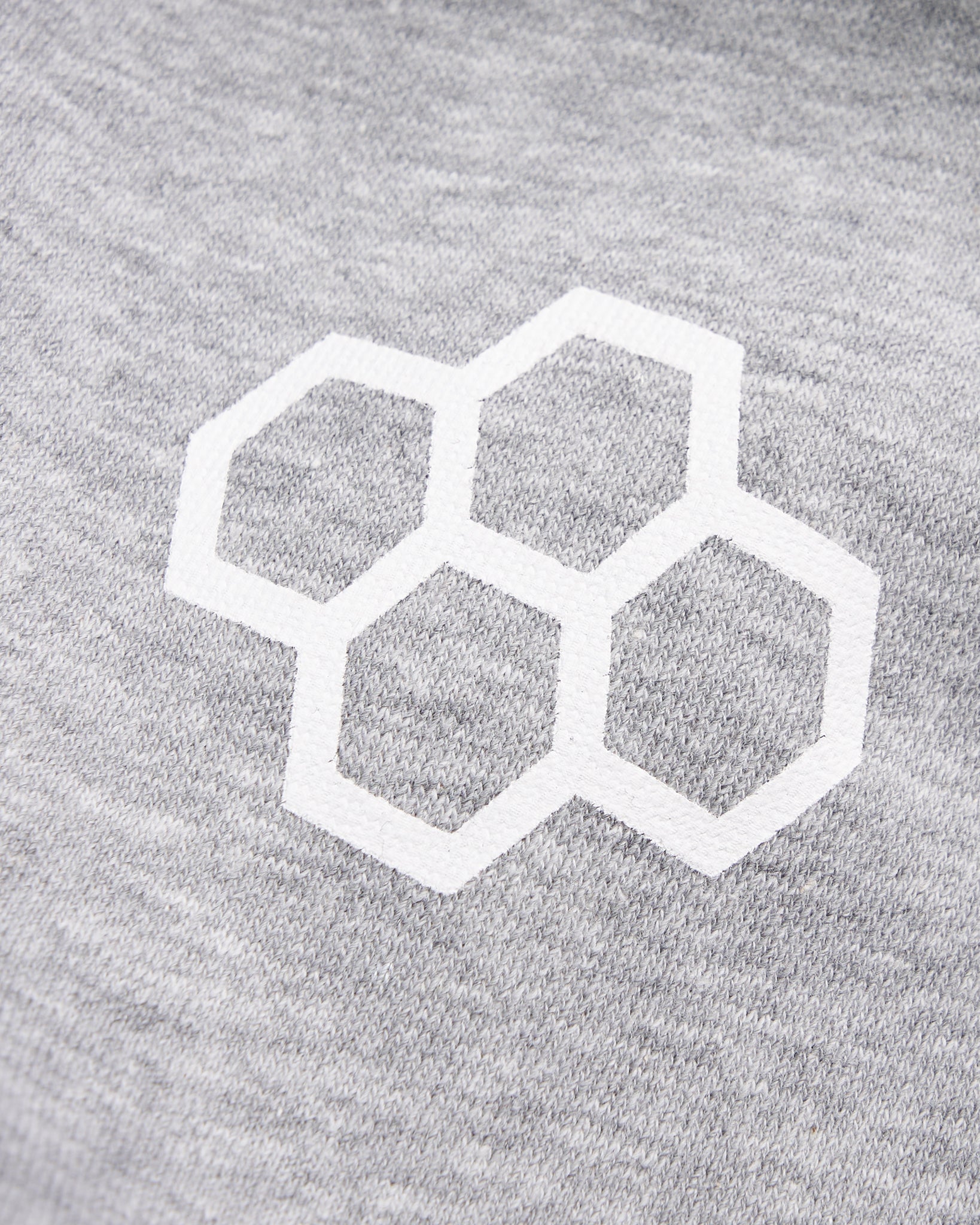 The image depicts a close-up of a light gray fabric featuring a white honeycomb pattern stitched into it