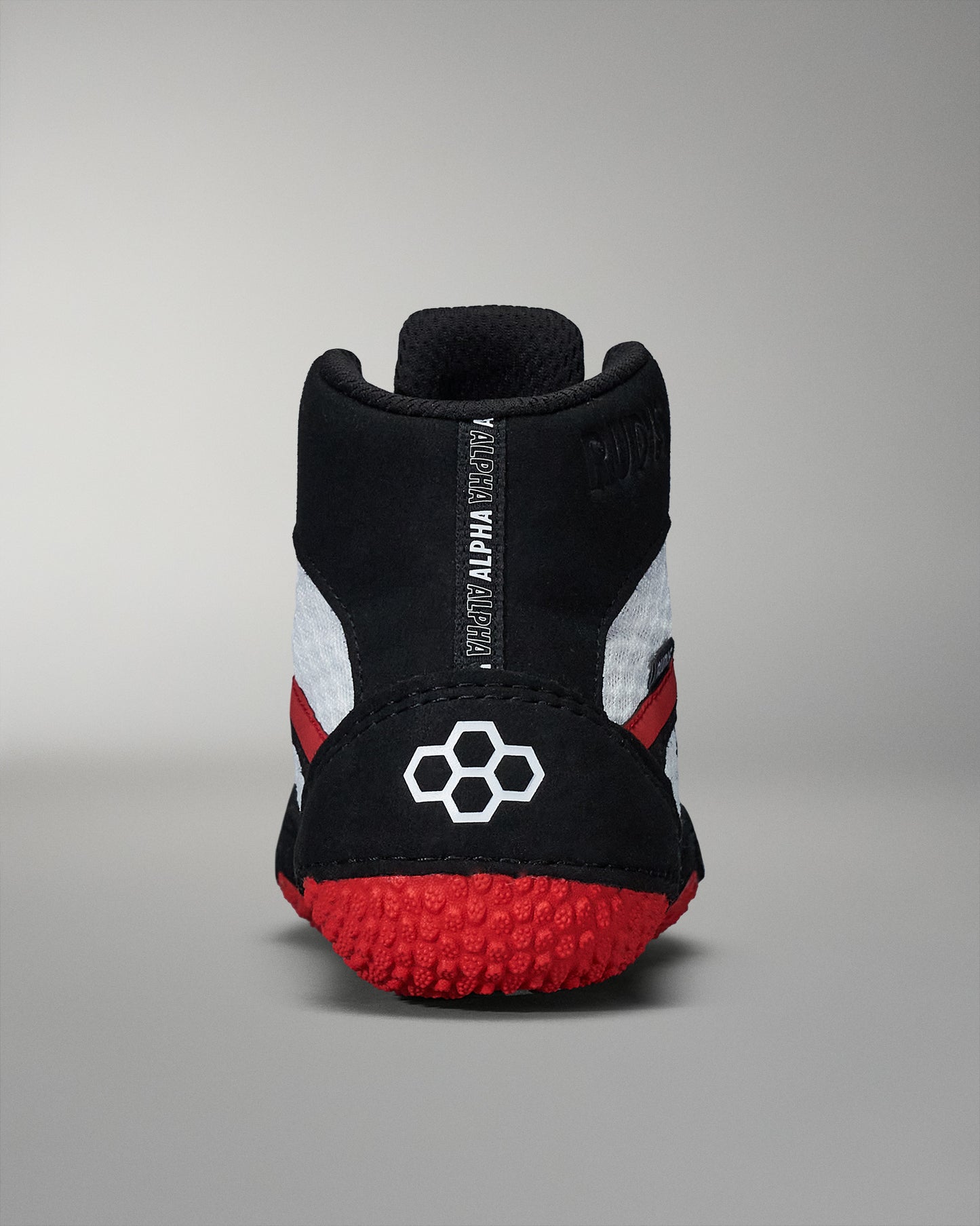 A sporty black and gray athletic shoe with red accents and a textured grip on the sole, highlighting ALPHA branding on the heel.