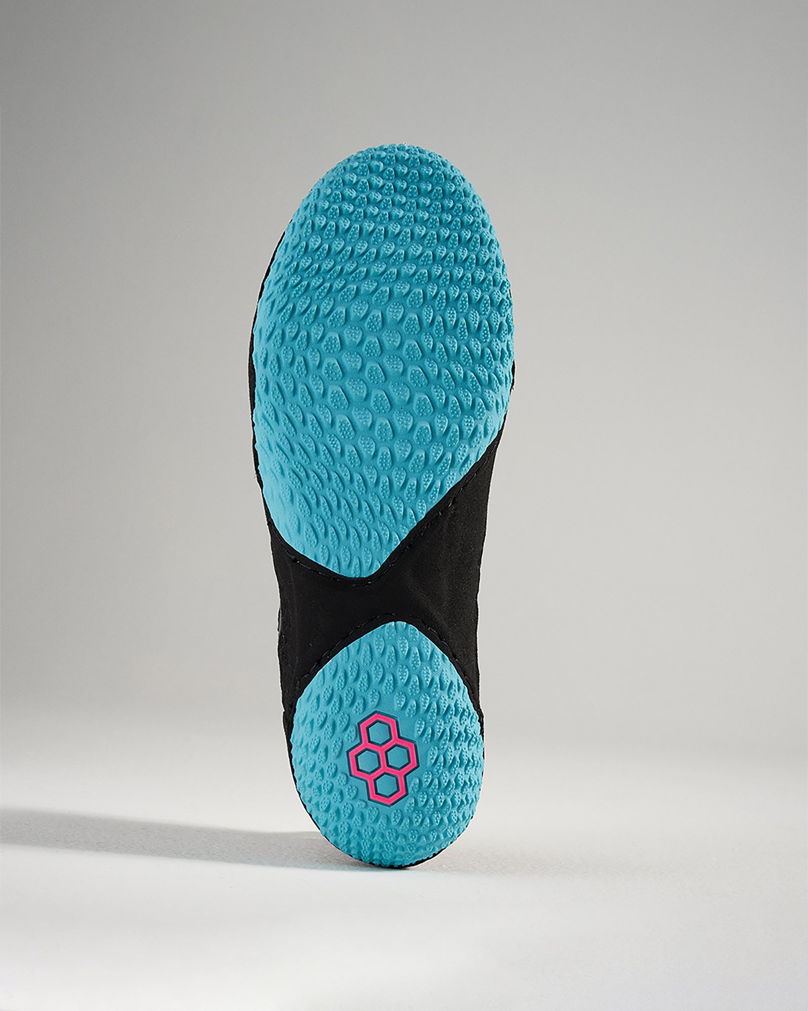 The image displays the outsole of a black athletic shoe featuring a textured blue sole with a prominent logo in pink emphasizing its design and functionality