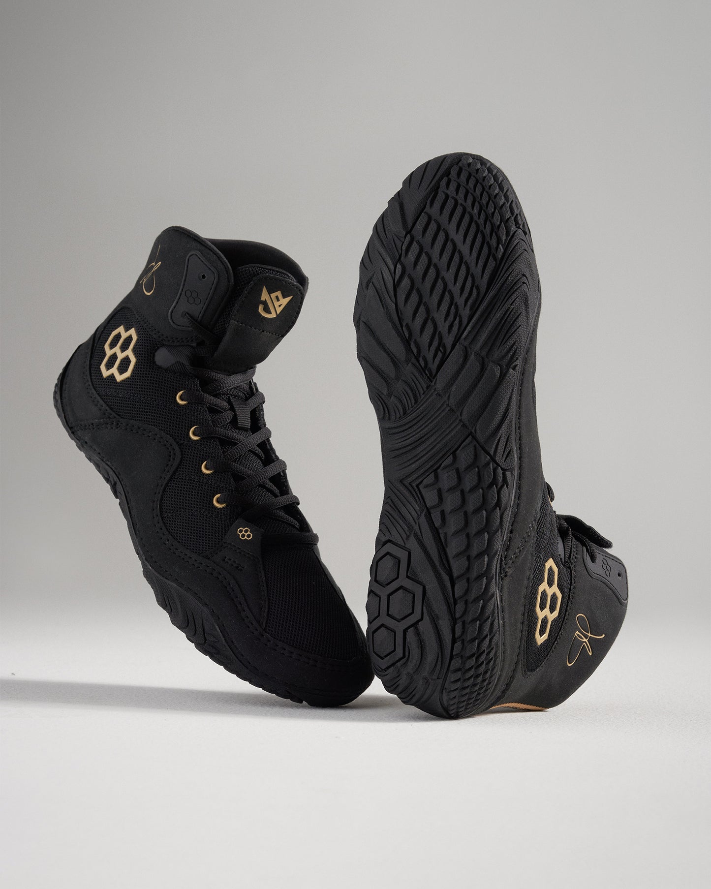 This image showcases a pair of modern black athletic shoes featuring a sleek design contrasting gold accents and a textured rubber sole for enhanced grip