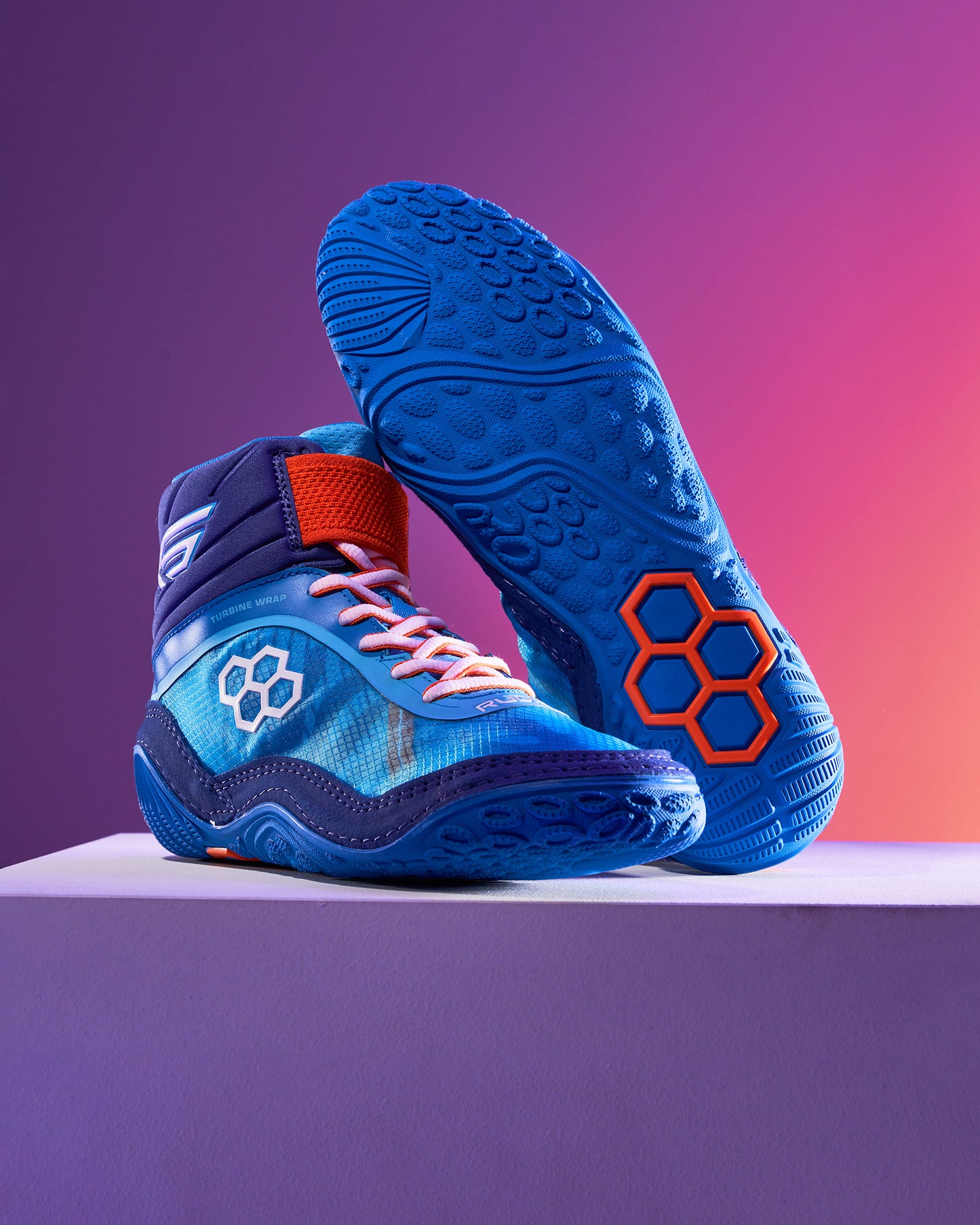 Vibrant blue athletic shoes with intricate designs and a textured sole showcased on a light pedestal against a gradient background