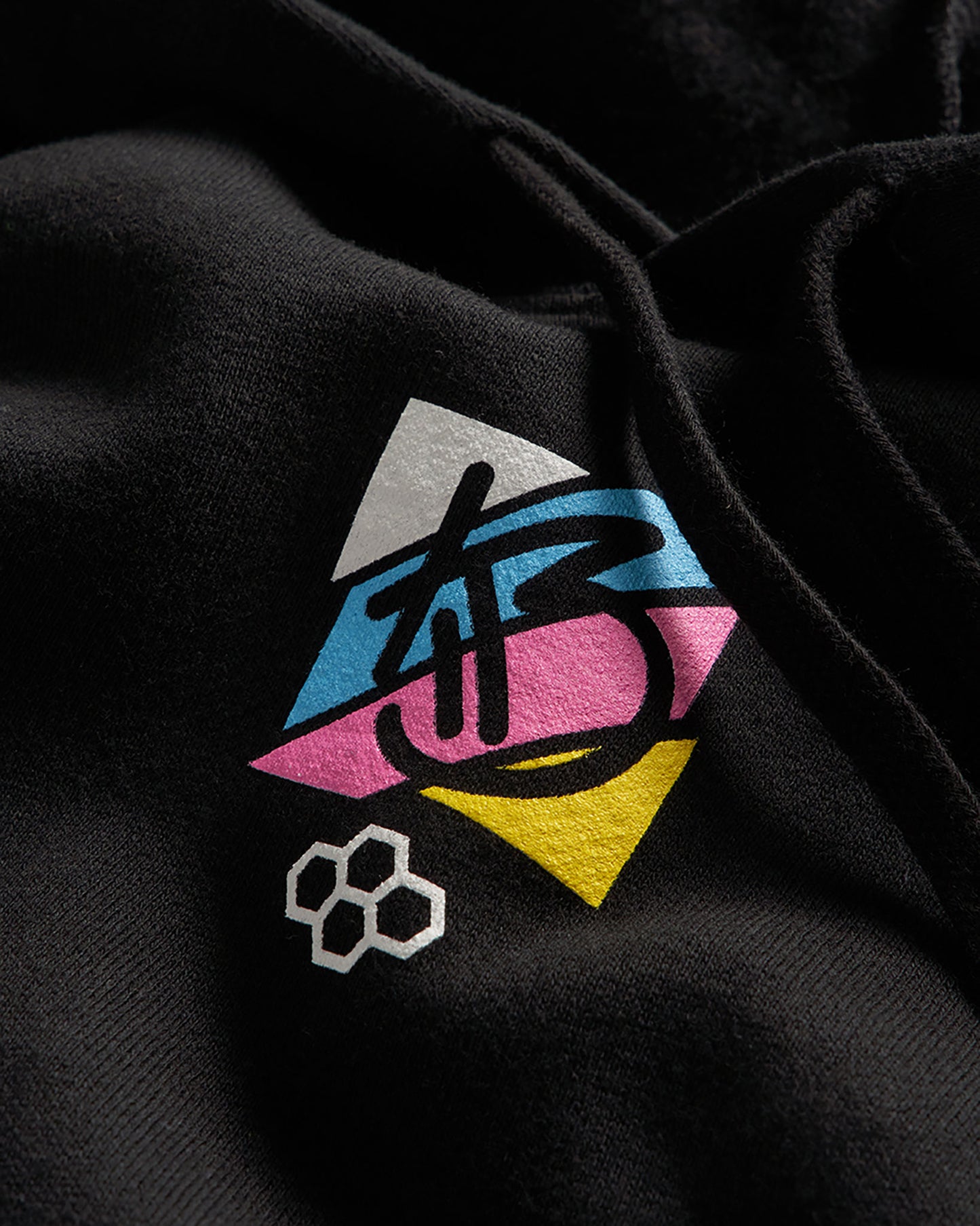 A close-up of a black hoodie displaying a colorful geometric logo with artistic lettering