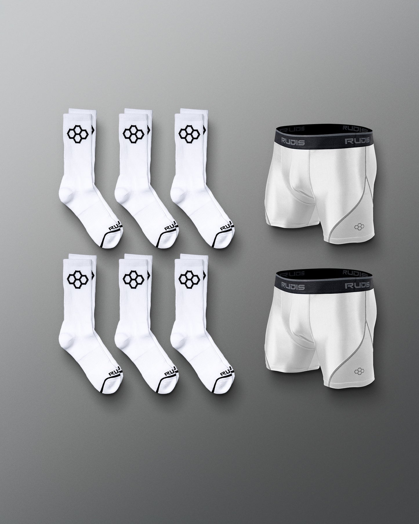 A neatly arranged collection of white athletic socks and boxer briefs with black branding set against a soft gray background.