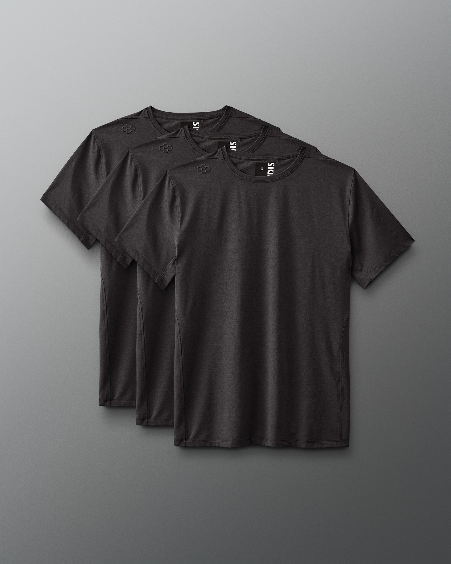 Three black t-shirts arranged against a gray background highlight a minimalist style, featuring short sleeves and a soft, uniform fabric.