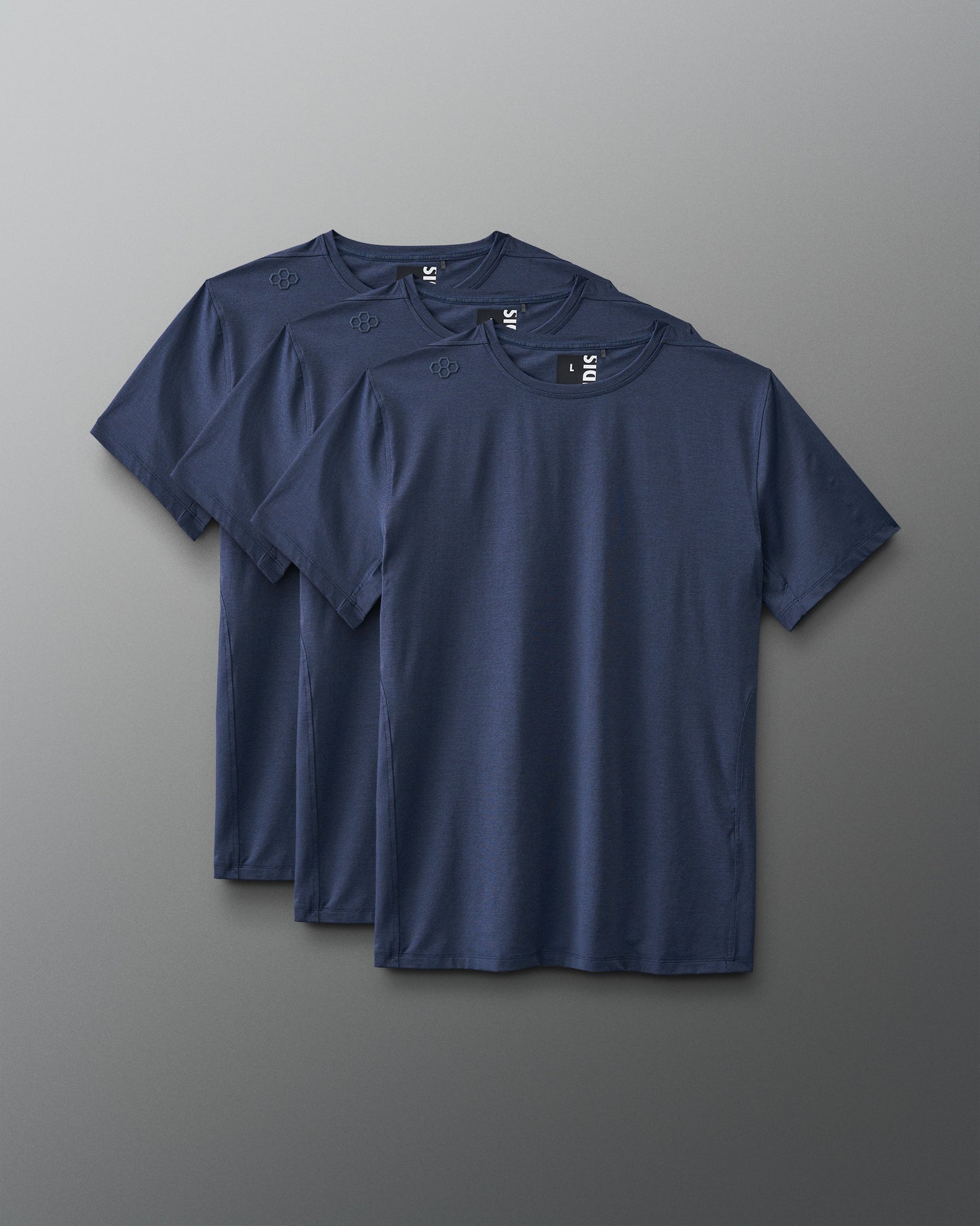 Three navy blue t-shirts, featuring round necklines and short sleeves, are neatly stacked against a muted gray background, showcasing their simple design and texture.