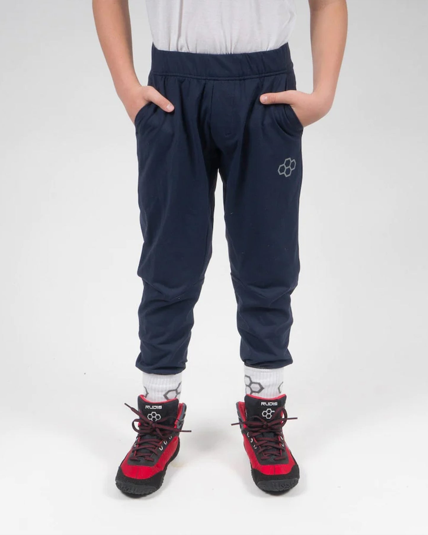 A child stands confidently in navy blue pants paired with red and black athletic shoes showcasing a lively and casual look