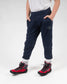 A child stands confidently wearing navy athletic pants and bold red sport shoes showcasing a casual and active style