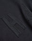 Close-up of a black fabric surface featuring a prominent textured letter H stitched in a contrasting fabric