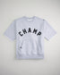 A gray sweatshirt with the word CHAMP printed in bold black letters across the front featuring a cozy hood and a front pocket