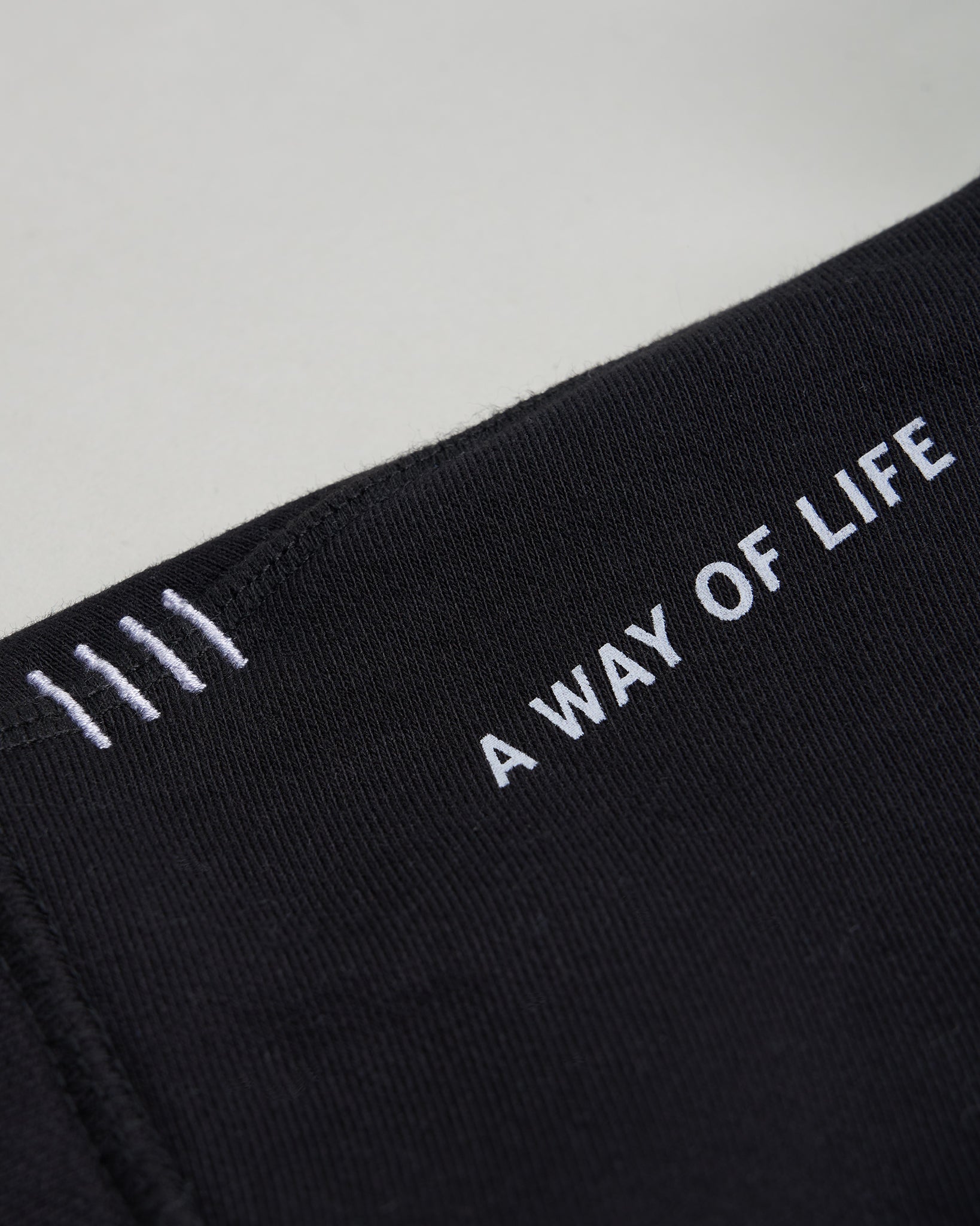 This image features a close-up view of a black fabric band with the phrase A WAY OF LIFE embroidered in white text