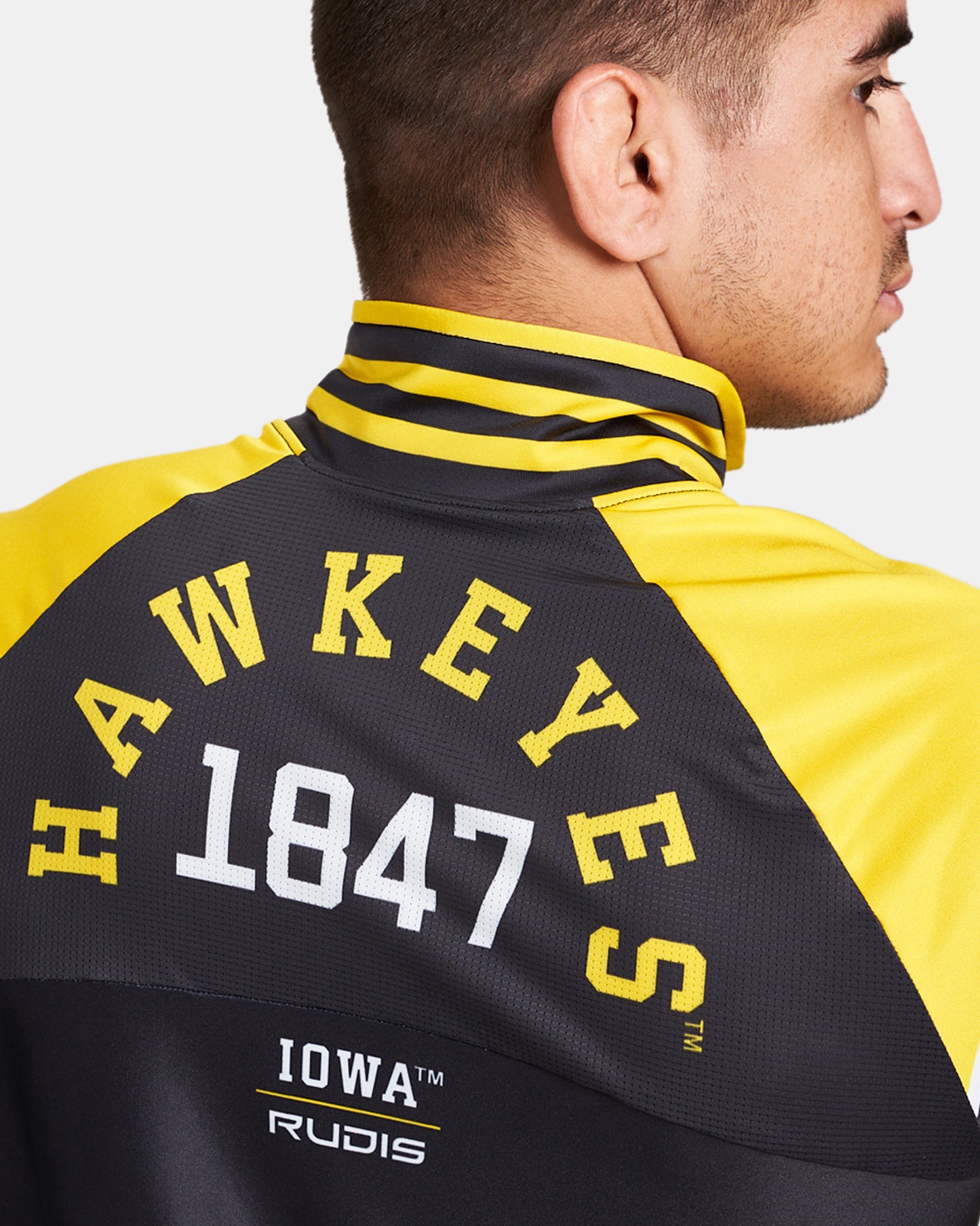 A close-up view of a man wearing a stylish yellow and black Hawkeyes jacket featuring prominent lettering and branding