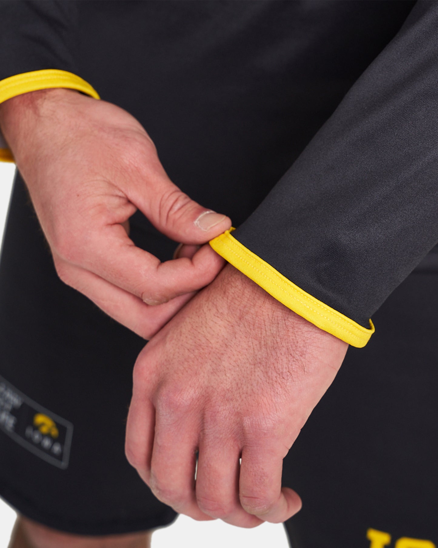 A close-up view of a person adjusting the yellow cuffs of a black athletic shirt showcasing a focus on detail and design