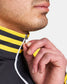 A close-up of a man in a black athletic top with a yellow striped collar unzipping the neck area with his right hand