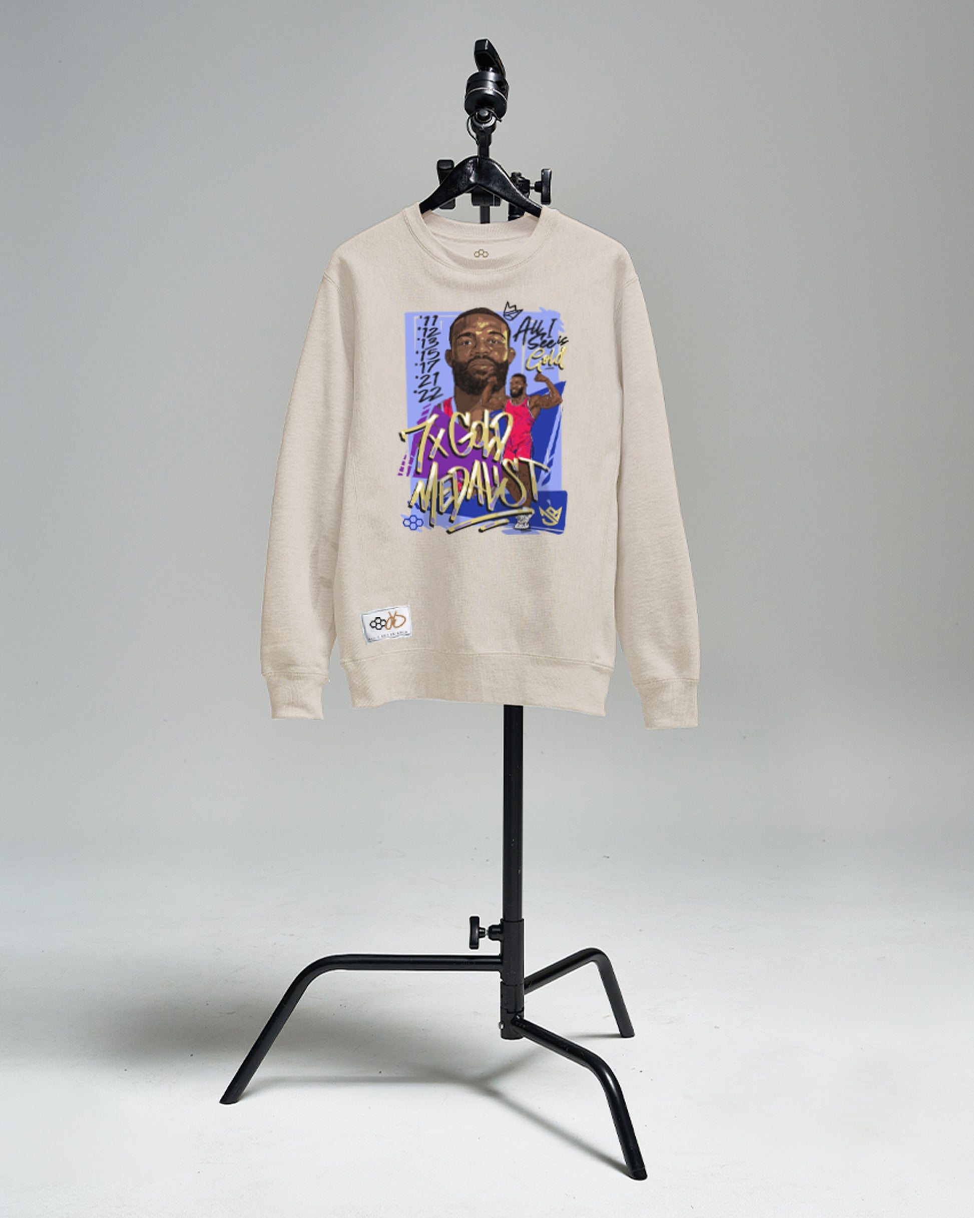 A beige sweatshirt featuring a vibrant graphic of an athlete highlighting their achievements and golden medal status