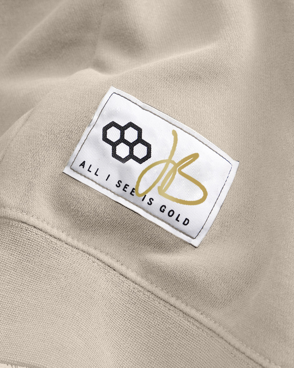 This image features a close-up of a clothing label on a beige fabric showcasing a unique logo and a motivational phrase