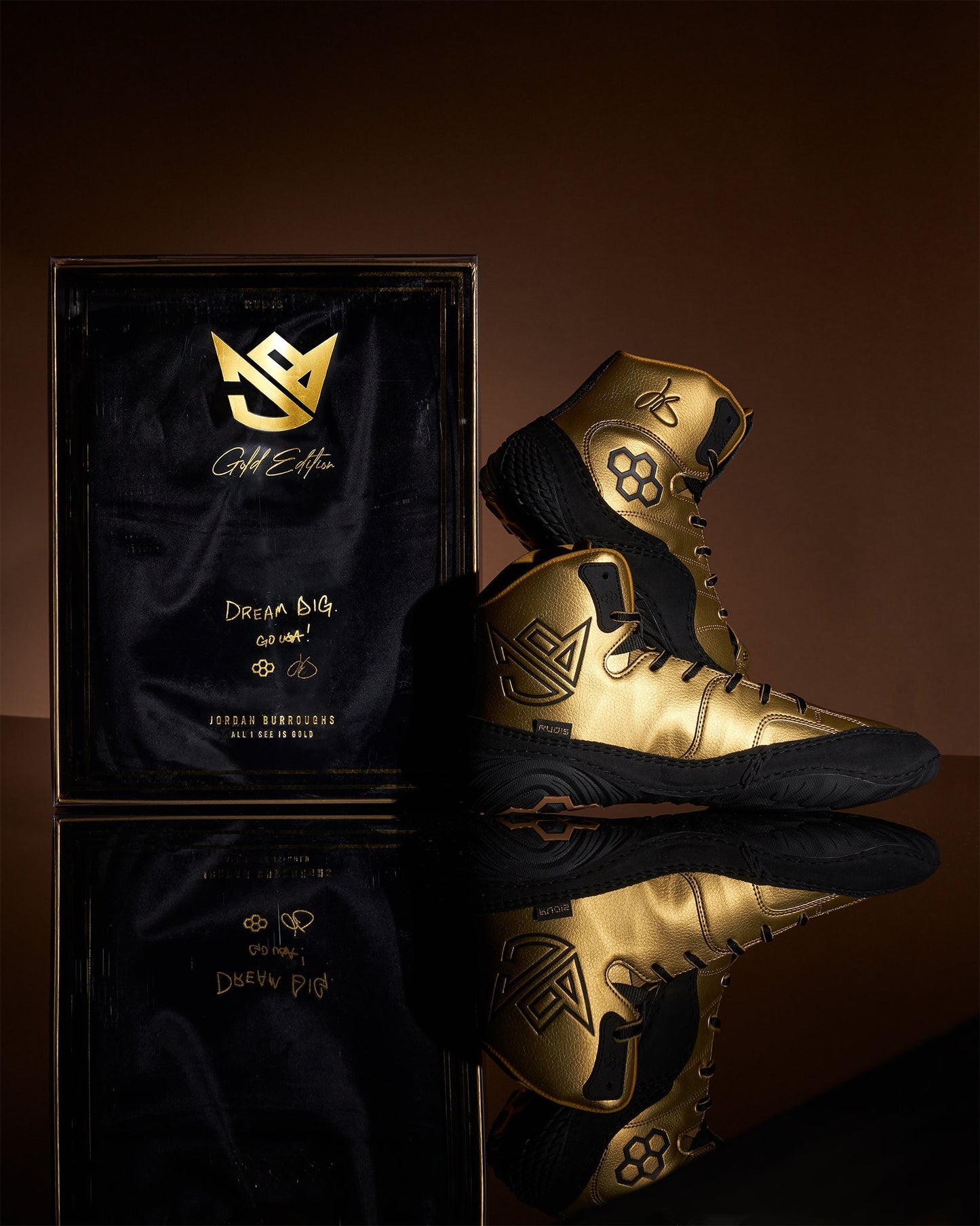 A striking pair of black and gold athletic shoes displayed next to an elegant packaging box showcasing a luxurious design and inspirational branding