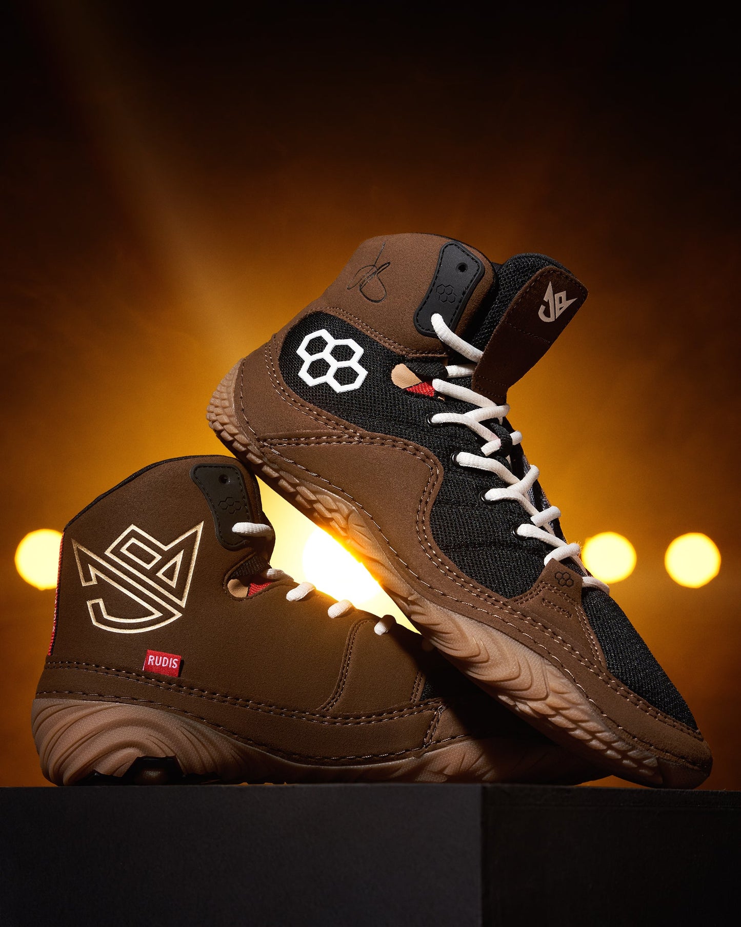 High-top athletic shoes with a brown upper and black accents are showcased against a warm, glowing background, highlighting their distinctive design.