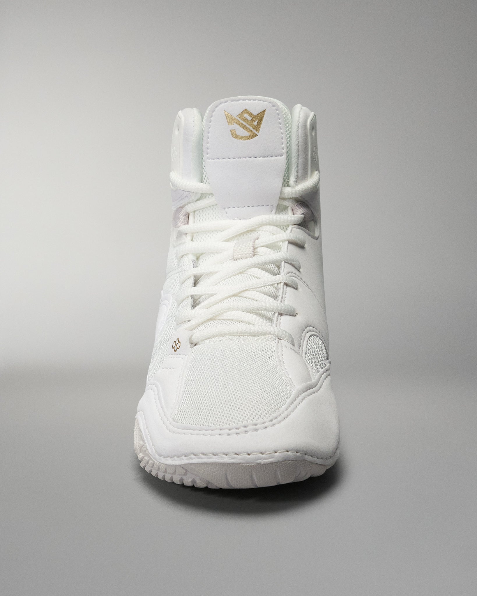 A white high-top athletic shoe combines a breathable upper with a padded collar and gold branding, designed for comfort and performance.