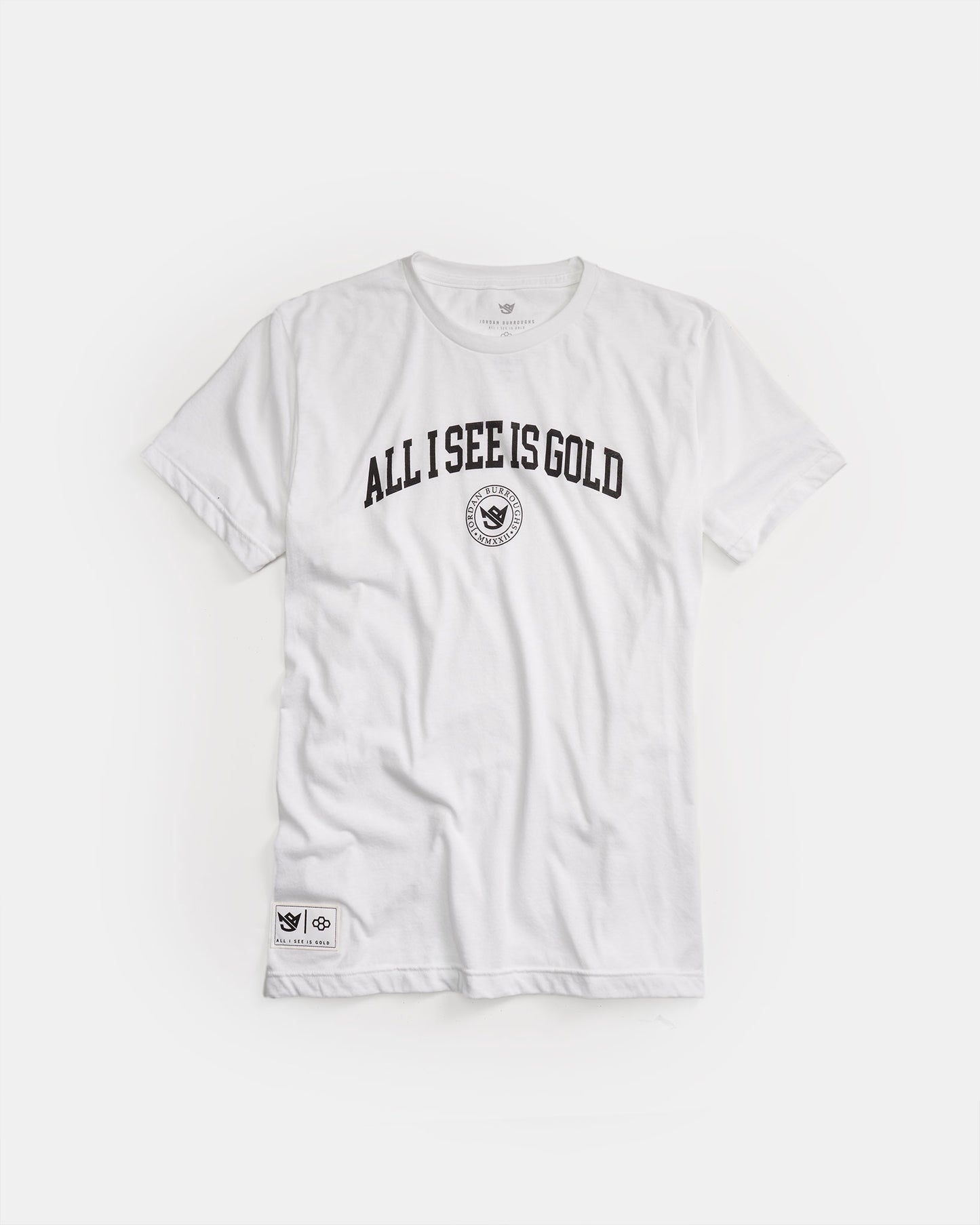 A stylish white t-shirt featuring the bold phrase ALL I SEE IS GOLD in black text accompanied by a circular logo at the center and a branded patch on the lower side