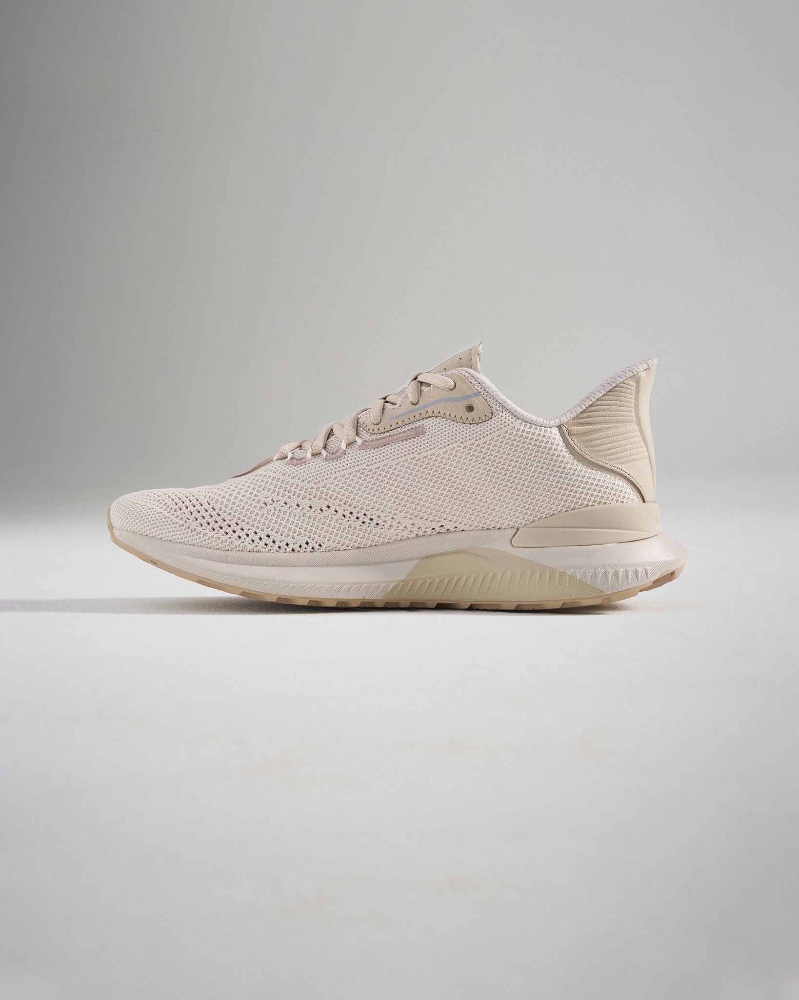 A stylish beige running shoe featuring a breathable mesh upper and a textured sole designed for comfort and performance