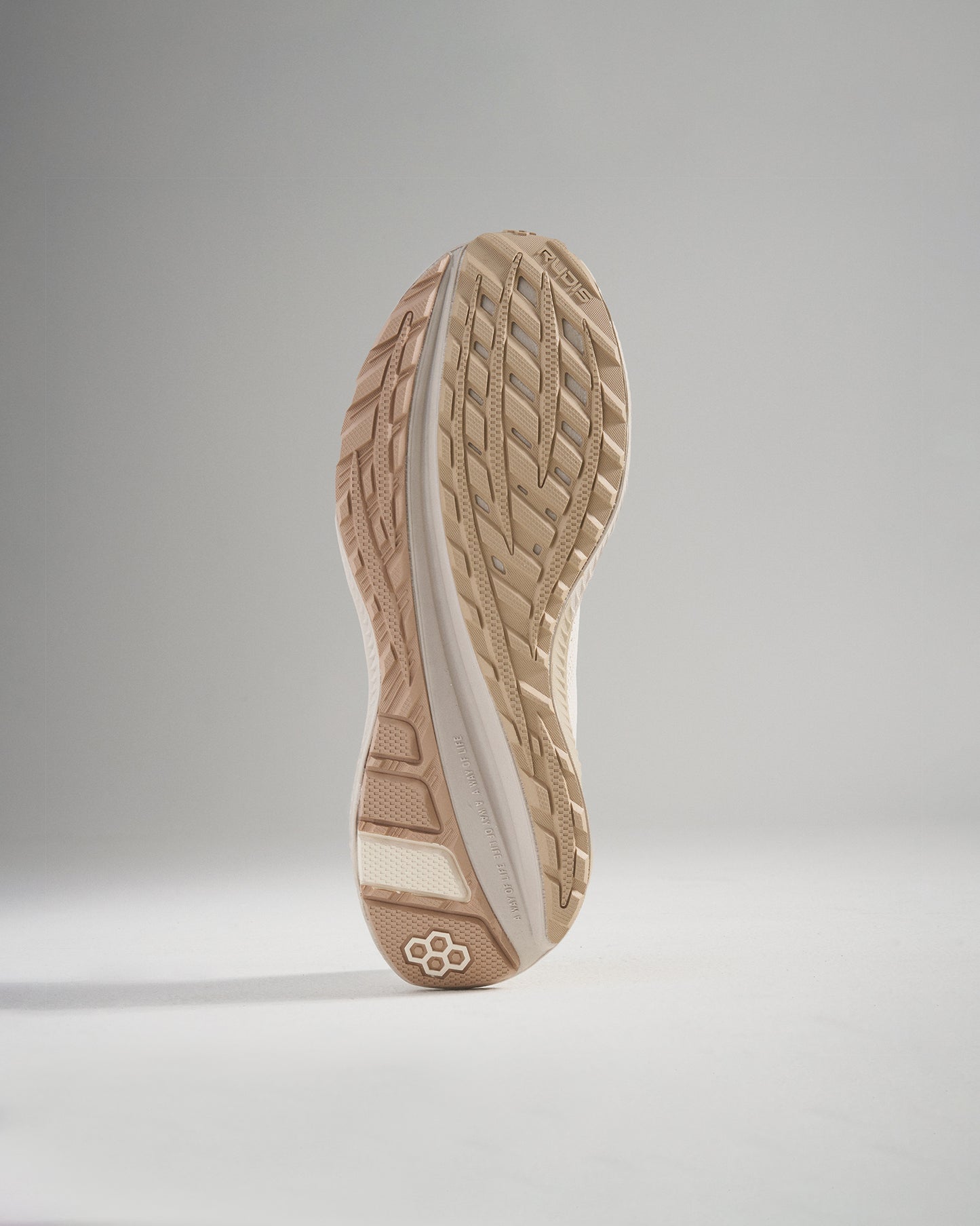 A close-up view of a beige athletic shoe sole featuring a textured grip pattern and lightweight design showcasing its functionality for sports and running