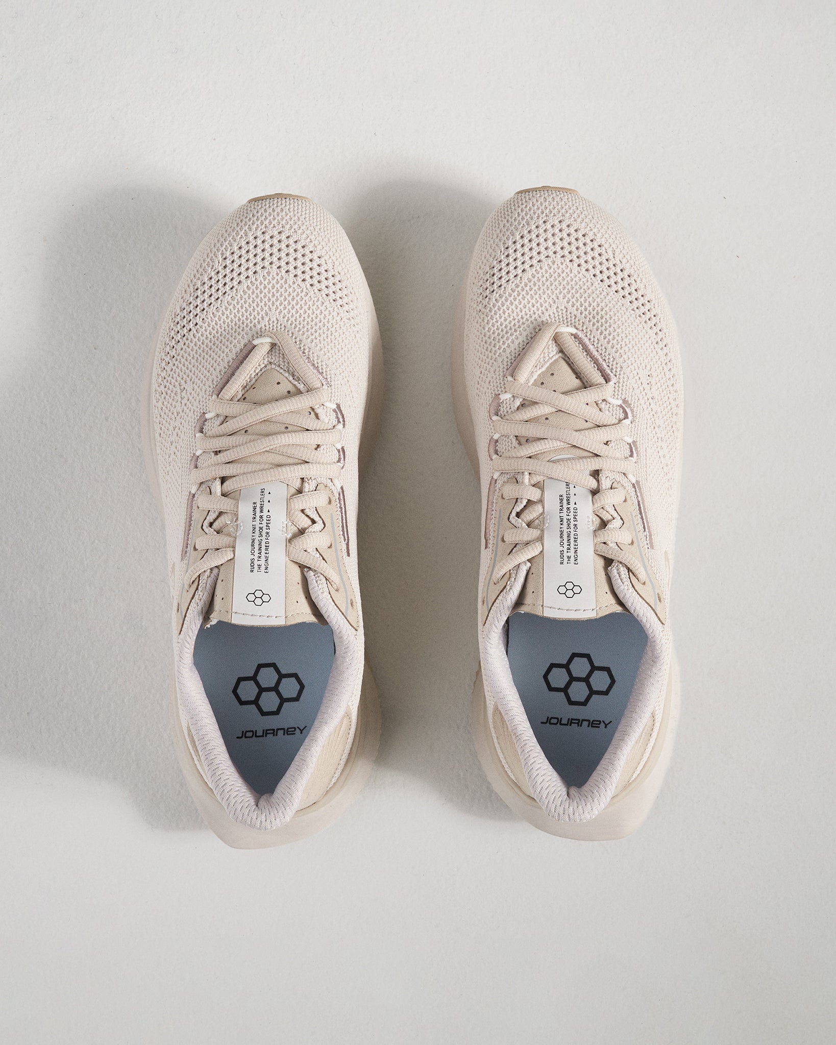 A top view of light beige athletic shoes showcasing a breathable mesh upper featuring a modern design and a prominent logo