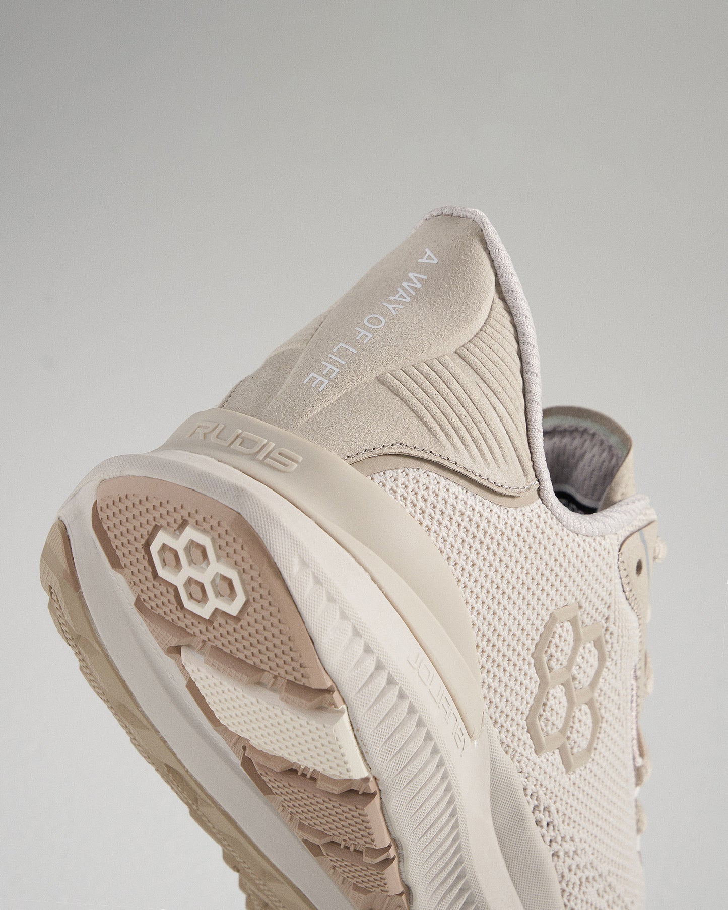 A light beige athletic shoe designed for performance showcasing innovative materials and textural details