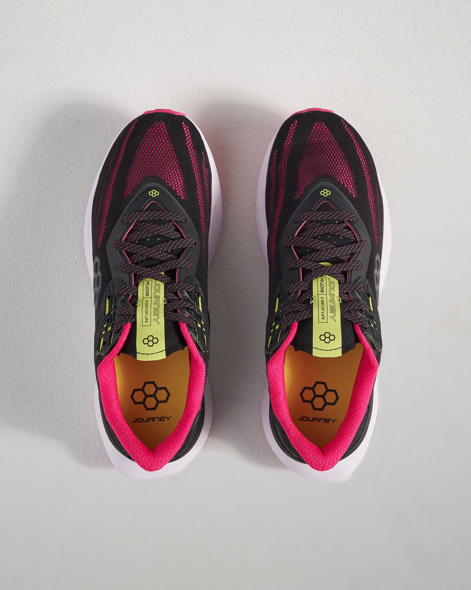 A top view of modern black running shoes featuring vibrant pink and yellow accents designed for comfort and performance