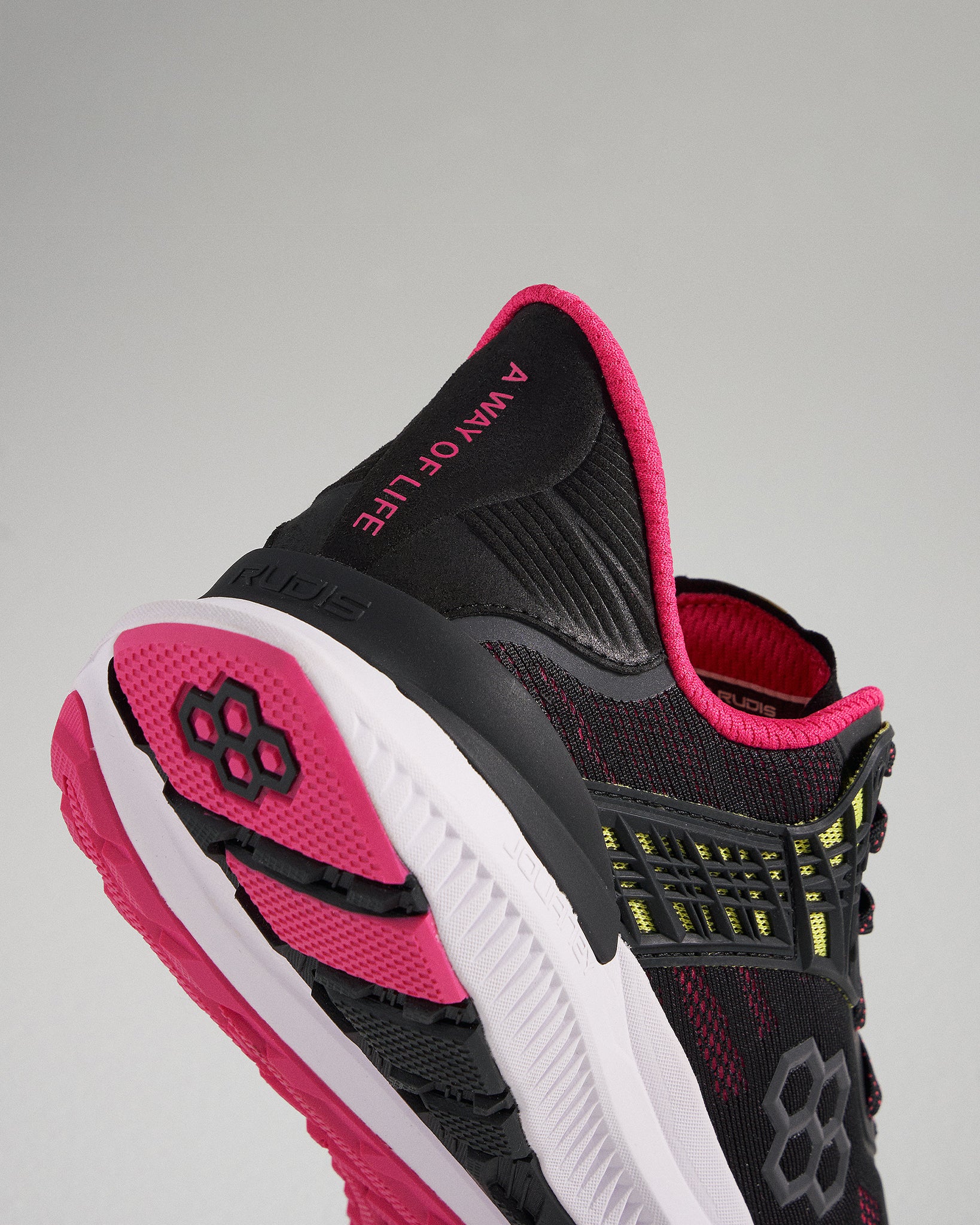 A close-up view of a modern black athletic shoe featuring bright pink and yellow accents designed for enhanced performance and style