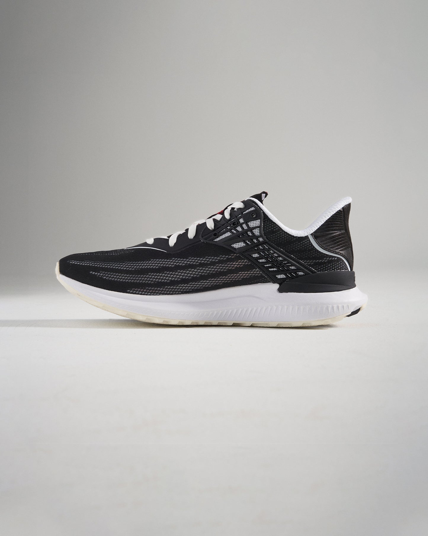 A side view of a modern black athletic shoe with a sleek design featuring breathable mesh and a durable sole