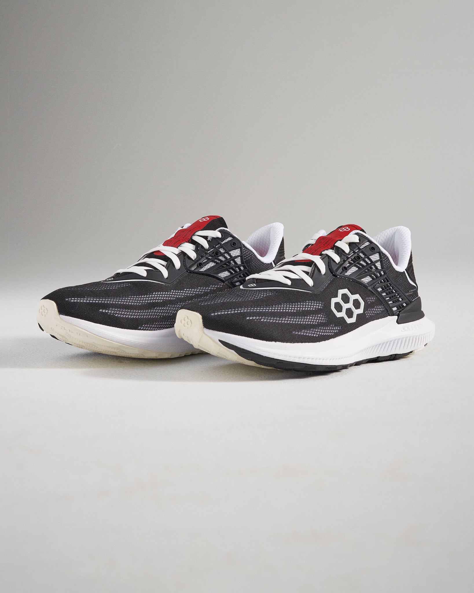 A pair of modern black athletic shoes with red accents designed for comfort and performance in running and casual wear