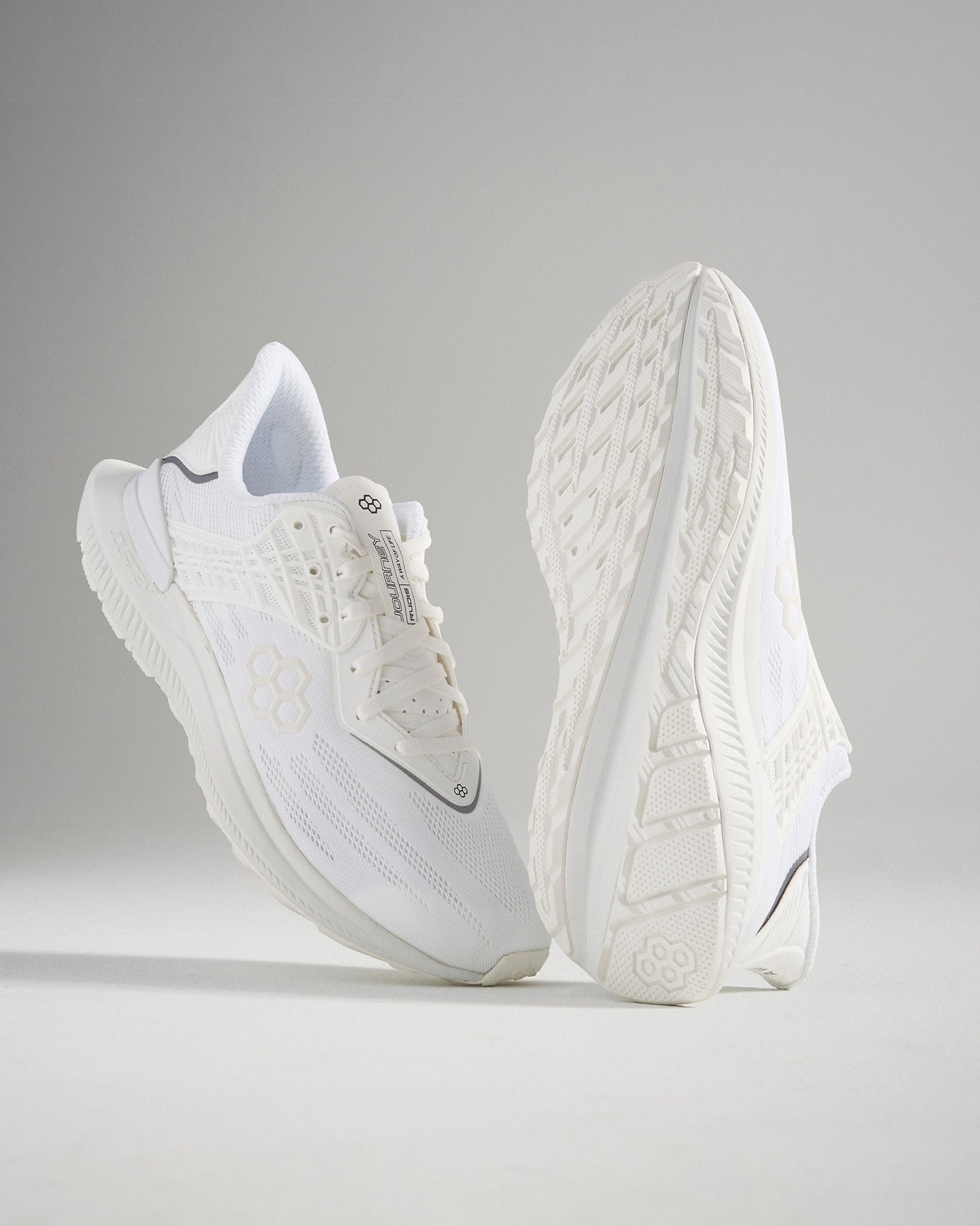 A pair of modern white athletic shoes showcasing a sleek design and textured detail on the upper and sole