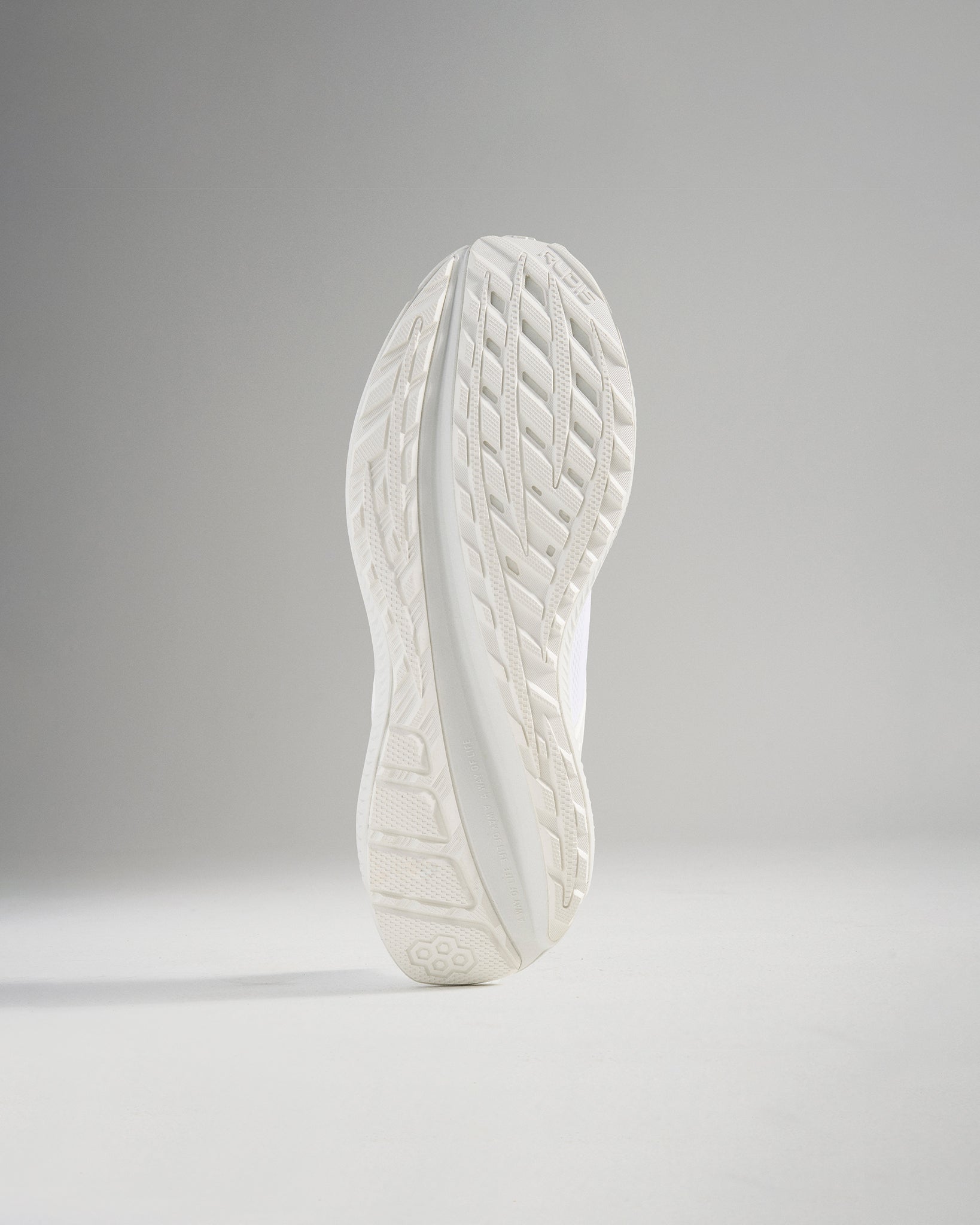 The image shows the sole of a white athletic shoe showcasing its textured grip and modern design